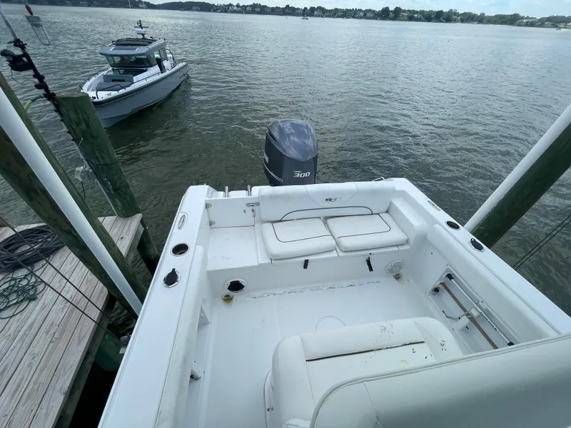 Slide: The Image of 2015 Sea Hunt Edge 24 boat docked, showing spacious deck and outboard motor. - 19