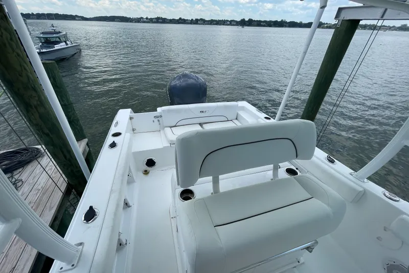 Slide: The Image of 2015 Sea Hunt Edge 24 boat docked by the water, featuring white seating and a rear motor. - 4