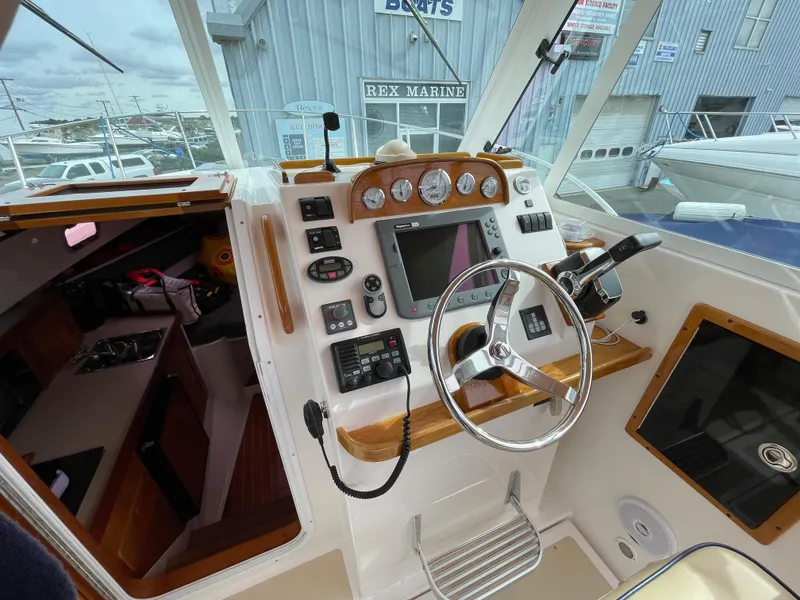 Slide: The Image of 2004 Hunt Yachts Surfhunter 29 with tan cover, parked near a black vehicle. - 5