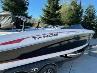 Slide: The Image of 2023 Tahoe 210 Si Limited boat on trailer, surrounded by trees. - 5