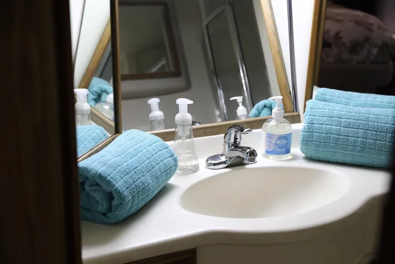 Slide: The Image of 1993 Sea Ray Sundancer bathroom sink with blue towels and soap dispensers. - 23