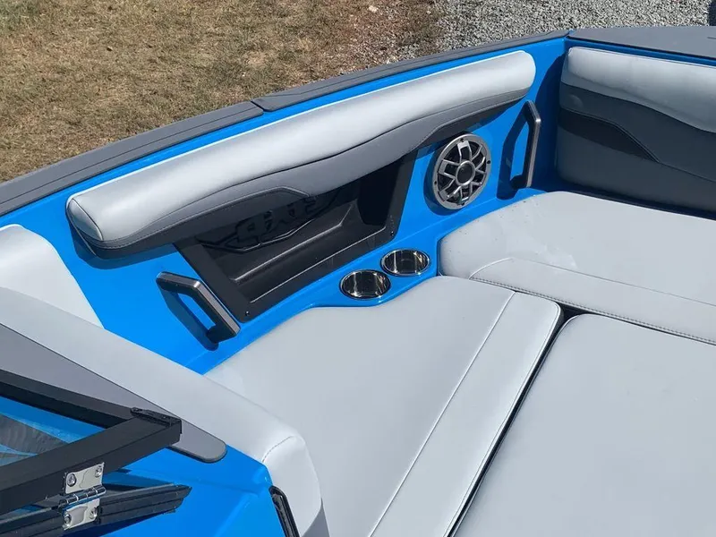 Slide: The Image of 2023 Axis T250 boat interior with blue and gray seating, cup holders, and speaker. - 13