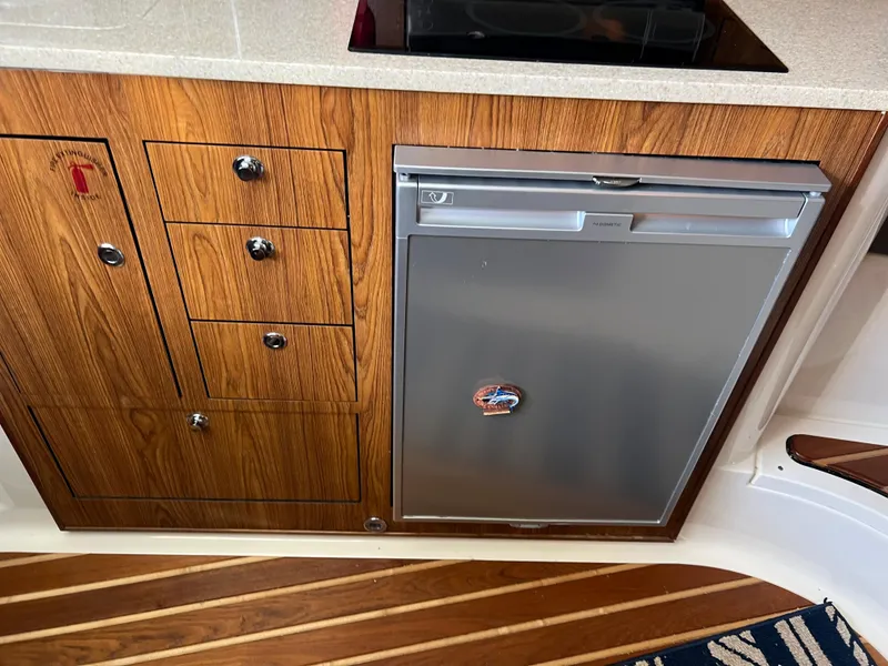 Slide: The Image of 2014 Pursuit 345 OS galley with wood cabinetry and stainless steel refrigerator. - 10