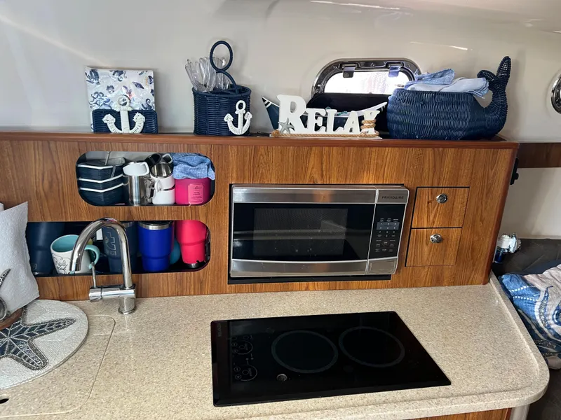Slide: The Image of 2014 Pursuit 345 OS kitchen with microwave, sink, and stove. - 12