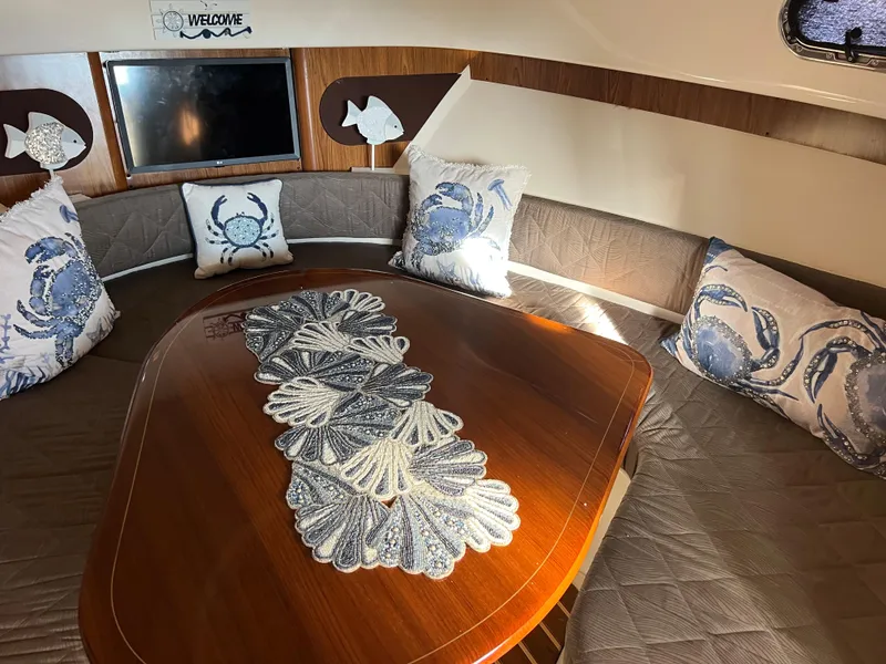 Slide: The Image of 2014 Pursuit 345 OS cabin with nautical-themed decor and wooden table. - 14
