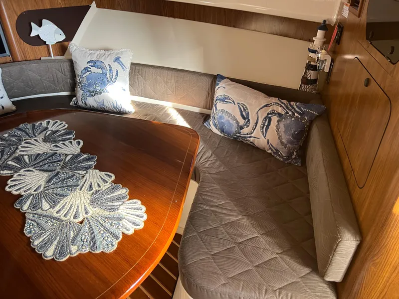 Slide: The Image of 2014 Pursuit 345 OS cabin interior with cushioned seating and decorative pillows. - 15
