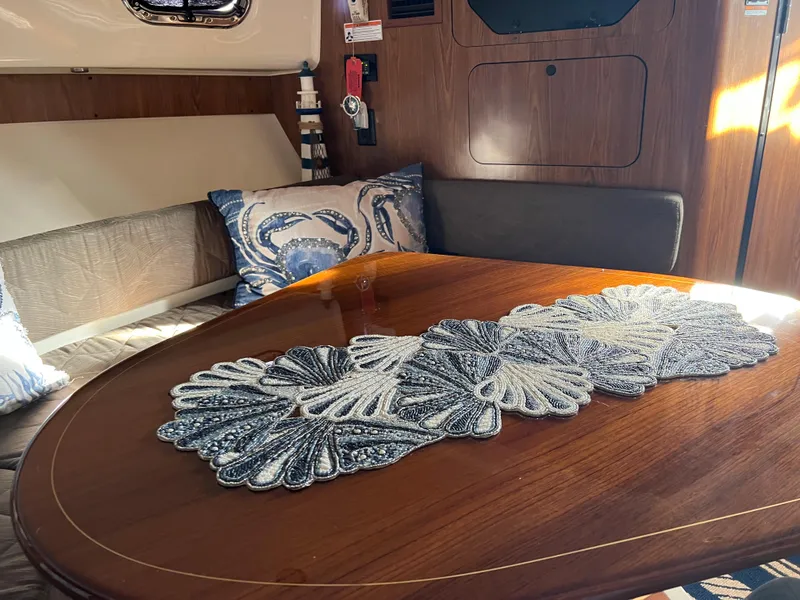 Slide: The Image of 2014 Pursuit 345 OS cabin interior with wooden table and decorative runner. - 19