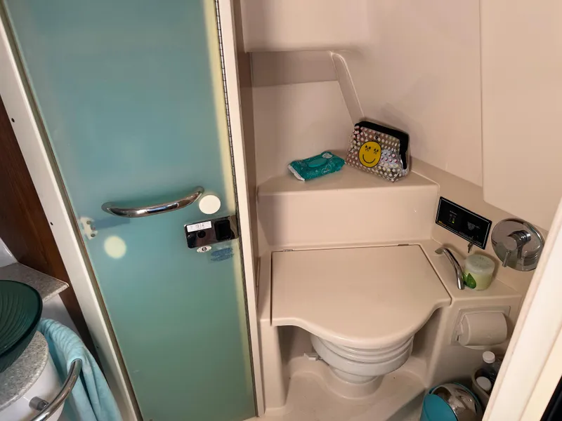 Slide: The Image of 2014 Pursuit 345 OS boat bathroom with toilet, sink, and storage shelves. - 22