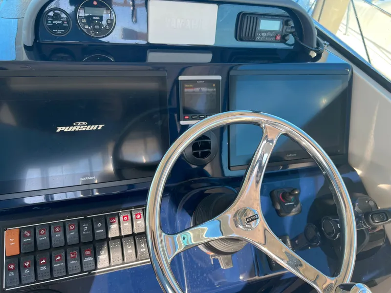 Slide: The Image of 2014 Pursuit 345 OS boat dashboard with steering wheel, gauges, and electronic displays. - 24