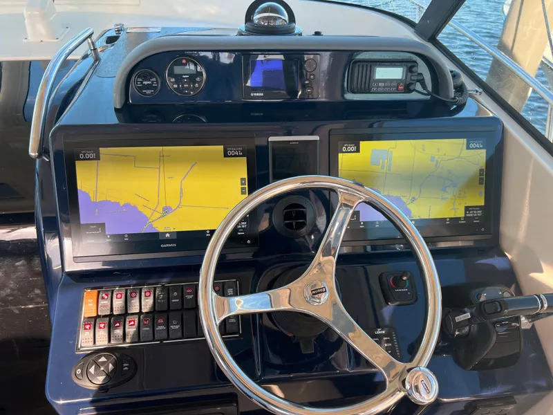 Slide: The Image of 2014 Pursuit 345 OS boat dashboard with navigation screens and steering wheel. - 25