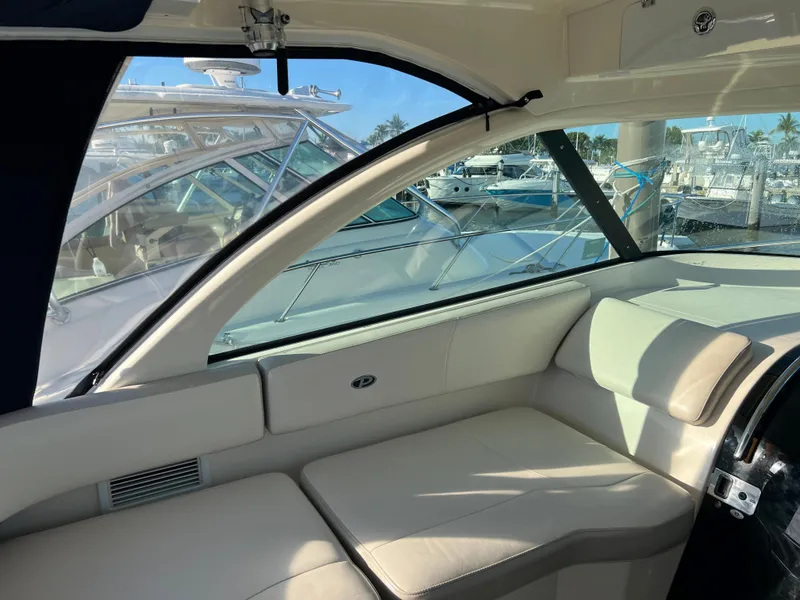 Slide: The Image of Interior of a 2014 Pursuit 345 OS boat with beige seating and marina view. - 32