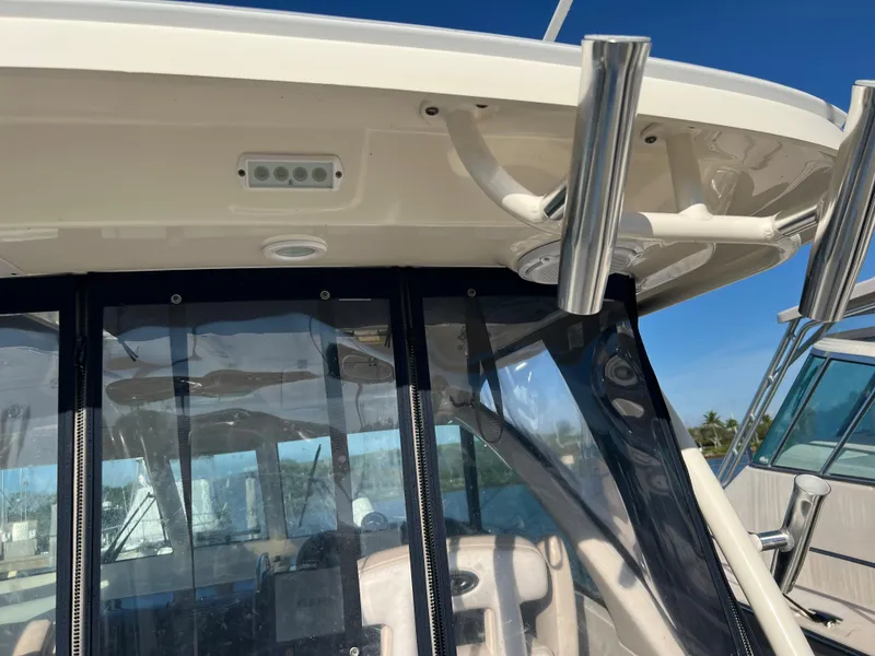 Slide: The Image of 2014 Pursuit 345 OS boat cockpit with clear enclosure and rod holders. - 44