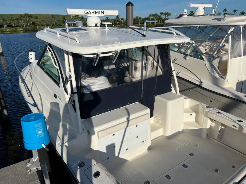 Slide: The Image of 2014 Pursuit 345 OS boat docked, featuring Garmin radar and spacious deck. - 6