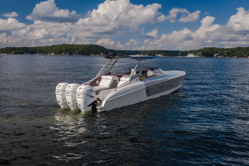 Slide: The Image of 2019 Donzi 41 GT boat cruising on a scenic lake under a partly cloudy sky. - 9