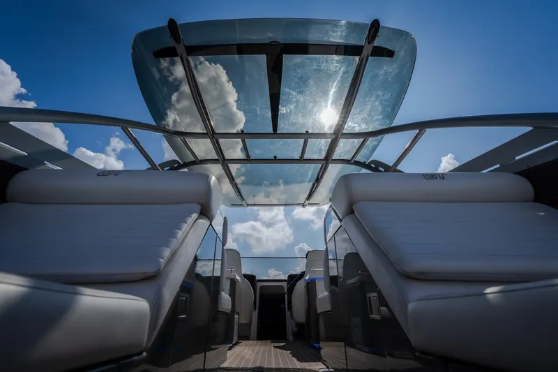 Slide: The Image of 2019 Donzi 41 GT boat interior with sleek seating and glass roof under blue sky. - 13
