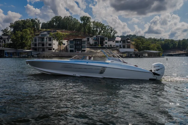 Slide: The Image of 2019 Donzi 41 GT boat cruising on a scenic lake with modern homes in the background. - 5