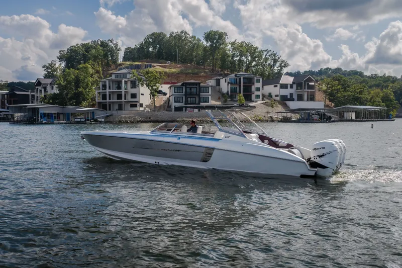 Slide: The Image of 2019 Donzi 41 GT boat cruising on a scenic lake near luxury waterfront homes. - 60