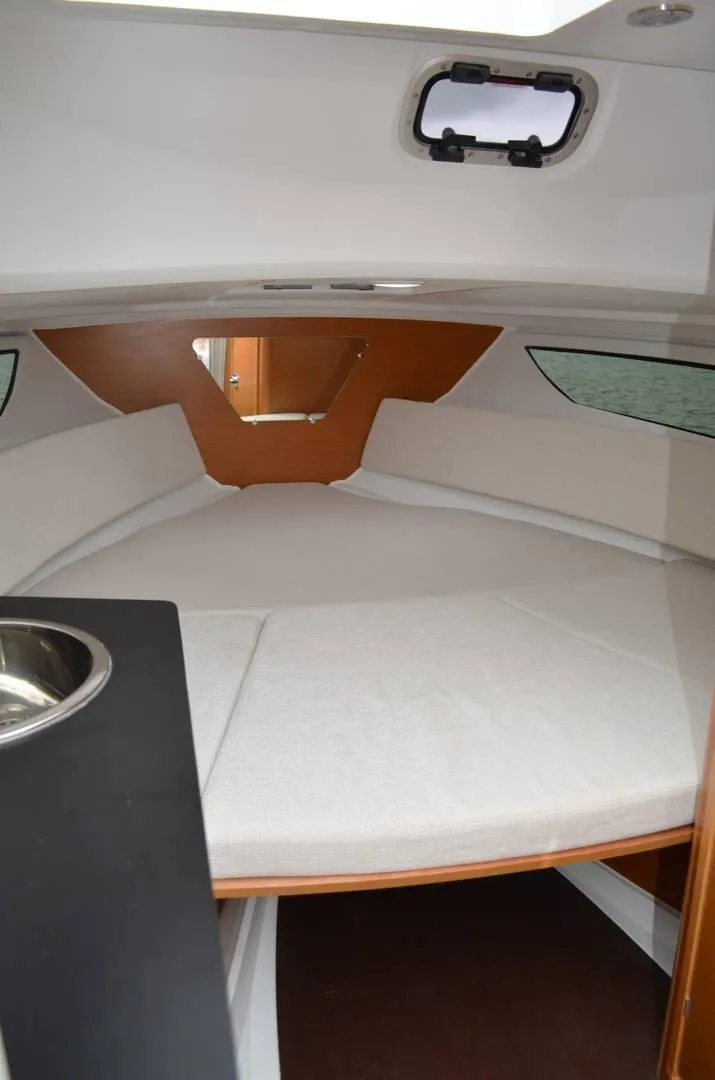 Slide: The Image of 2024 Jeanneau Leader 7.5 WA S3 cabin interior with bed and porthole. - 2
