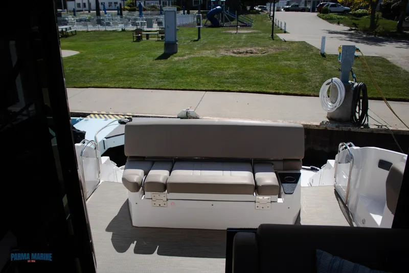 Slide: The Image of 2016 Regal 42 Sport Coupe boat interior with seating area, docked near grassy park. - 21