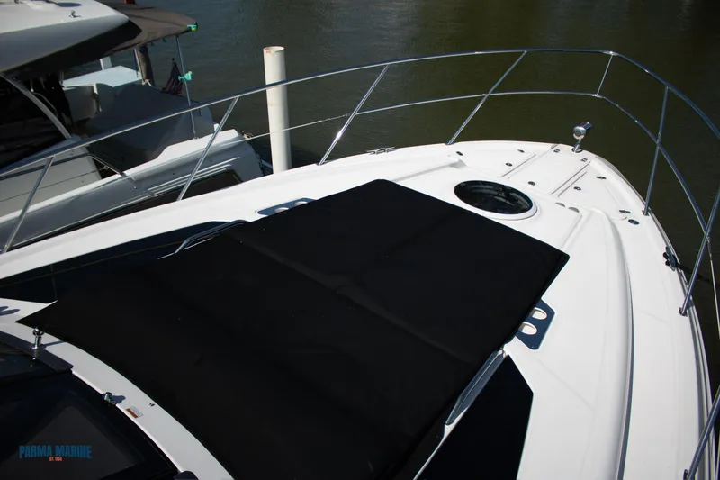 Slide: The Image of 2016 Regal 42 Sport Coupe yacht deck with black sunpad, docked on calm water. - 7