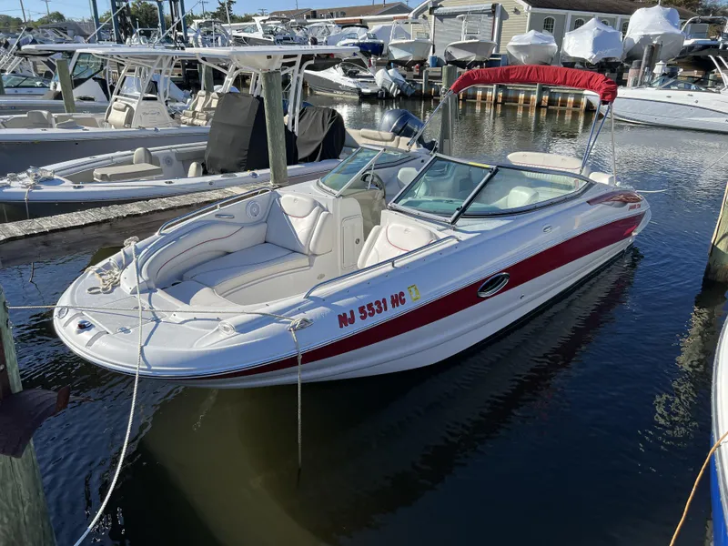 The Image of 2008 Crownline 240 EX boat docked in a marina with red and white exterior. - 1