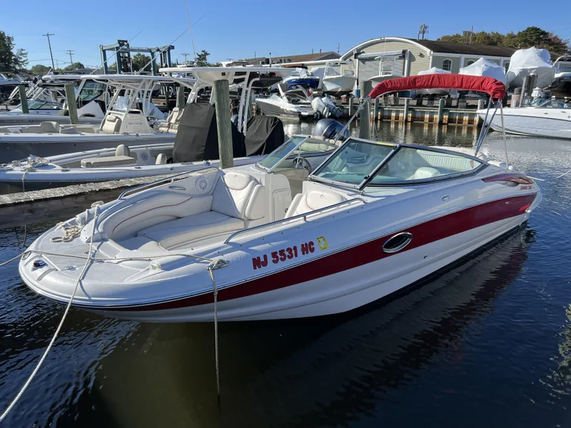 Slide: The Image of 2008 Crownline 240 EX boat docked in a marina with red and white exterior. - 10