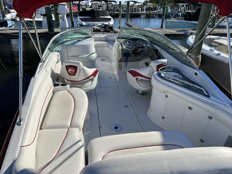 Slide: The Image of 2008 Crownline 240 EX boat interior with white and red seating at a marina. - 13