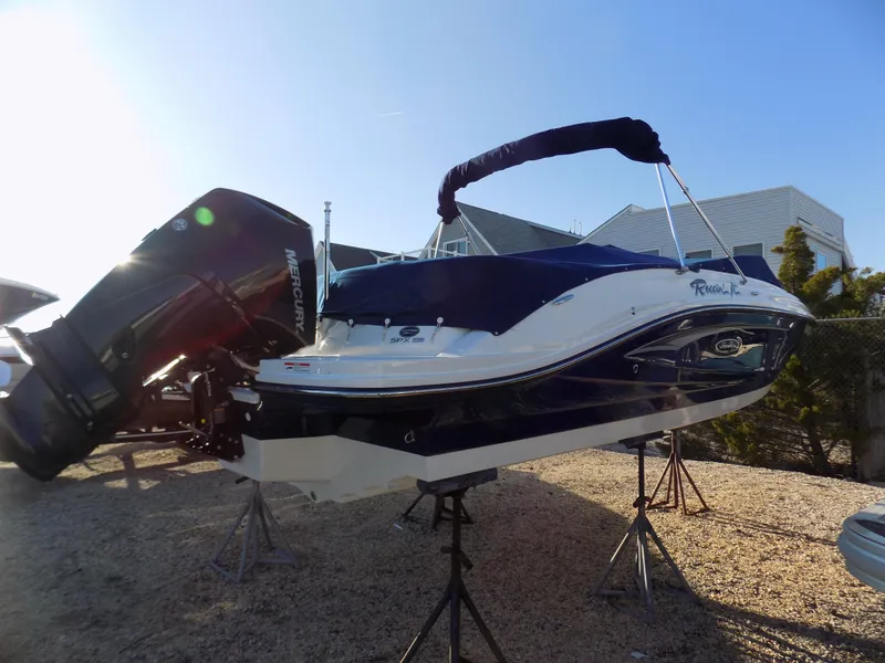 Slide: The Image of 2021 Sea Ray SPX 230 boat on stands, covered, with Mercury outboard engine. - 2