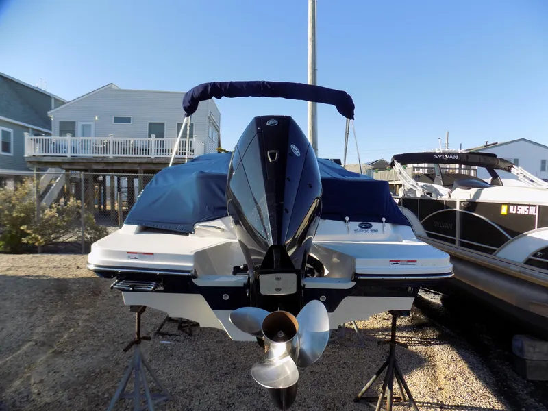 Slide: The Image of 2021 Sea Ray SPX 230 boat on stands, covered, with nearby houses and clear sky. - 4