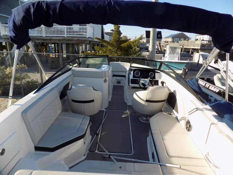 Slide: The Image of 2021 Sea Ray SPX 230 boat interior with seating, steering wheel, and canopy in a marina setting. - 7