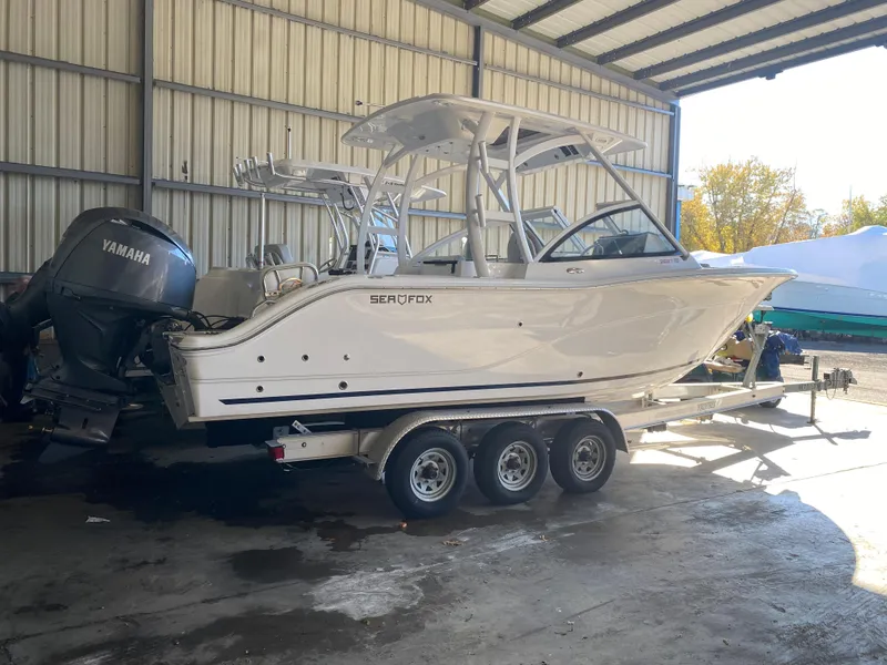 Slide: The Image of 2024 Sea Fox 268 Traveler boat on a triple-axle trailer in a covered storage area. - 2