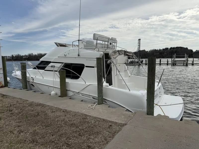 Slide: The Image of 2000 Silverton 35 Convertible yacht docked by a calm waterfront. - 3