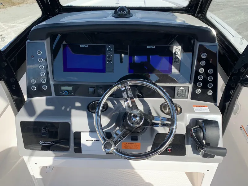 Slide: The Image of 2024 Robalo 266 Cayman boat dashboard with dual Simrad displays and Mercury controls. - 9