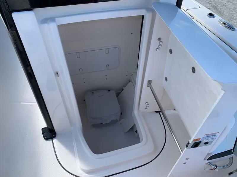 Slide: The Image of 2024 Robalo 266 Cayman boat storage compartment with portable toilet. - 16