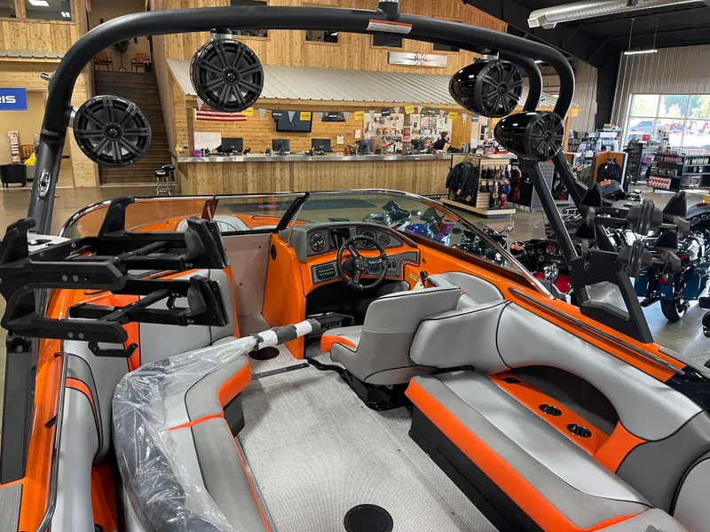 Slide: The Image of 2023 Sanger 237 SX boat interior with orange and gray seating, speakers, and dashboard. - 13