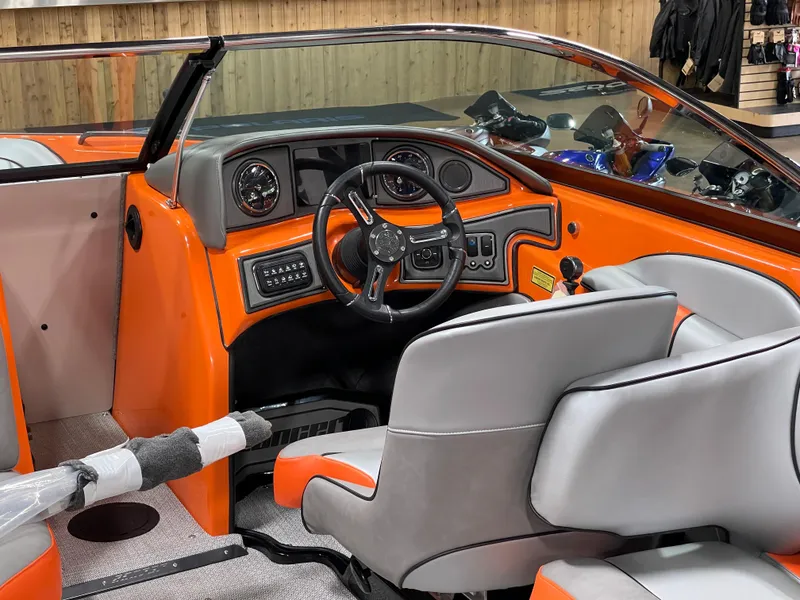 Slide: The Image of 2023 Sanger 237 SX boat interior with orange and gray seating and dashboard. - 16