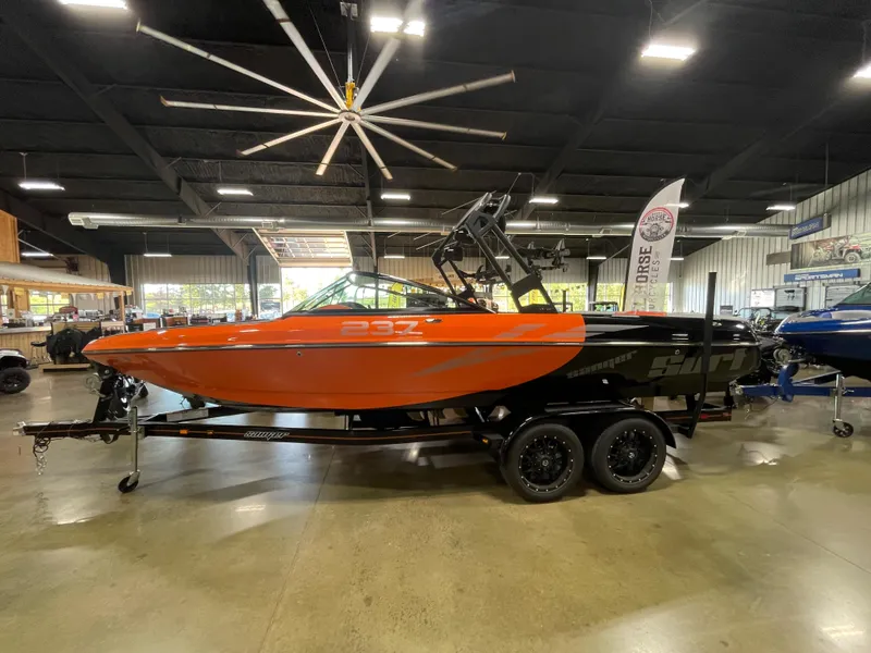 Slide: The Image of 2023 Sanger 237 SX boat in showroom, orange and black, on trailer. - 4
