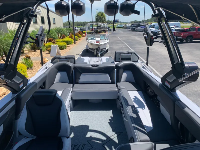 Slide: The Image of 2022 MasterCraft XStar S boat interior with seating and speakers, parked at a dealership. - 11