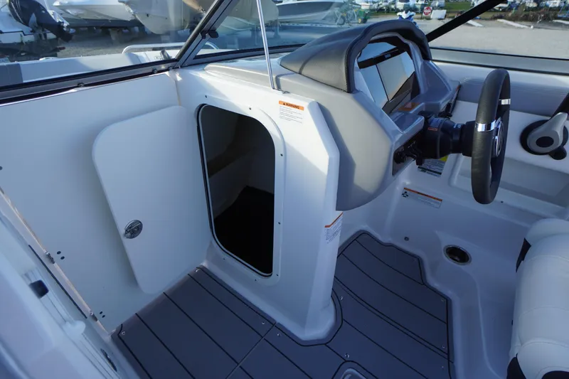 Slide: The Image of 2024 Chaparral 23 SSi OB boat interior with open storage compartment and steering console. - 19