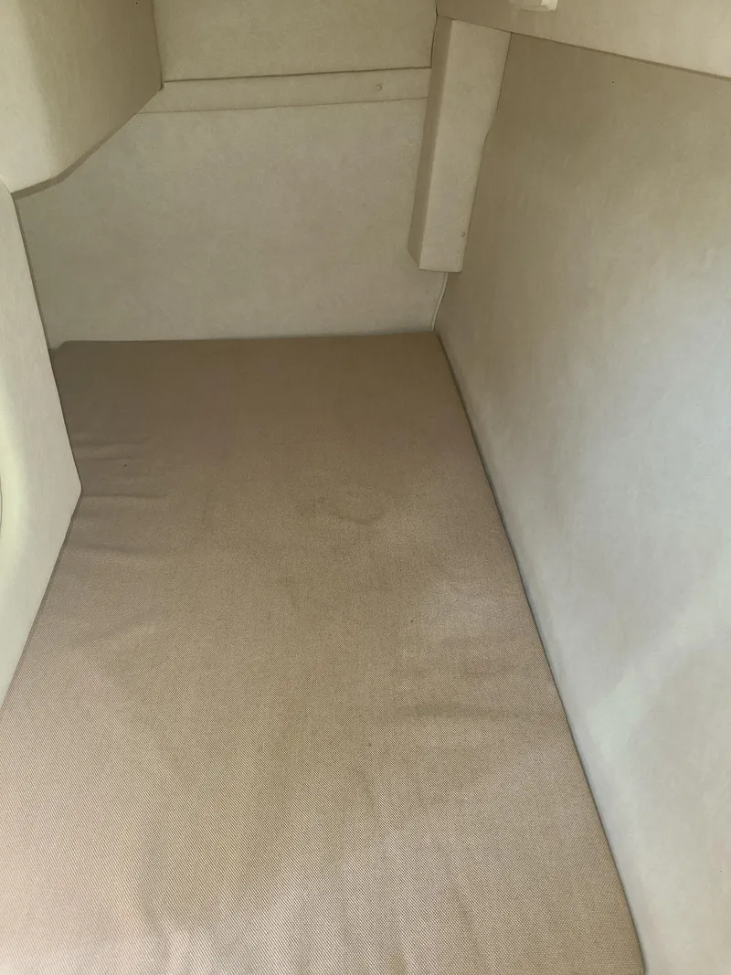 Slide: The Image of Interior cabin of 2010 Sea Ray 240 Sundancer boat, featuring beige upholstery. - 12