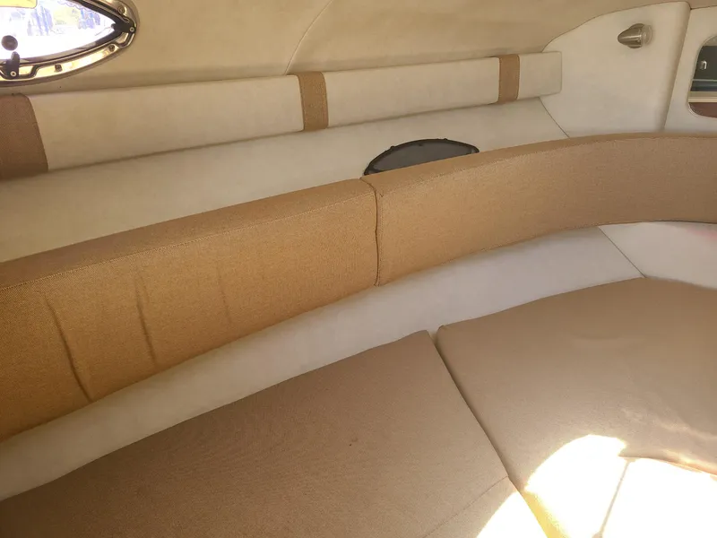 Slide: The Image of Interior cabin of 2010 Sea Ray 240 Sundancer with beige upholstery and porthole window. - 13