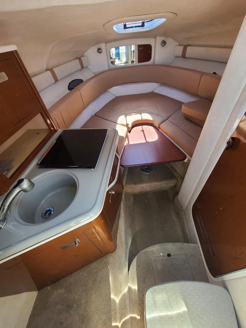 Slide: The Image of 2010 Sea Ray 240 Sundancer cabin interior with kitchenette, seating, and table. - 15