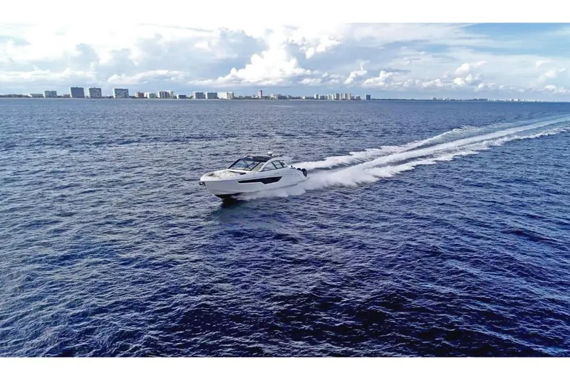 Slide: The Image of 2023 Cruisers Yachts 50 GLS speeding on open water with city skyline in the background. - 9