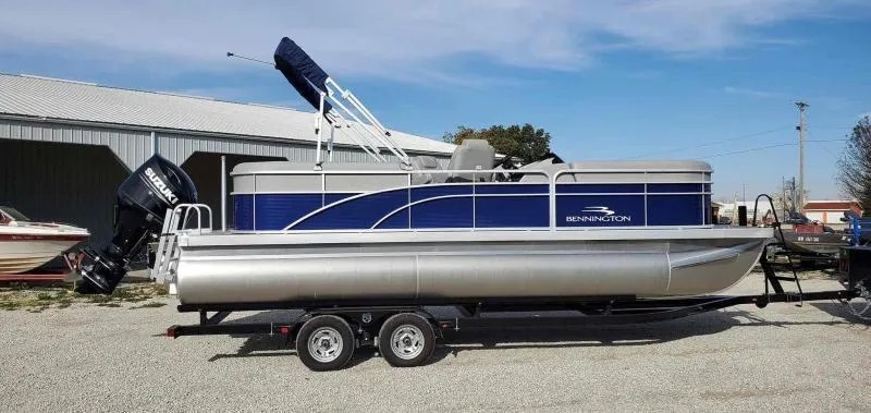 Slide: The Image of 2023 Bennington 22SVSR pontoon boat on trailer, blue and silver design, parked outdoors. - 5