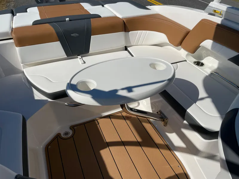 Slide: The Image of 2024 Chaparral 23 SSi OB boat interior with white and brown seating, table, and teak flooring. - 16