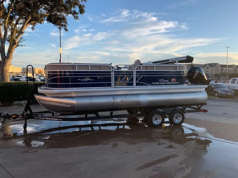 The Image of 2023 Sun Tracker Party Barge 20 DLX pontoon boat on trailer in parking lot. - 0