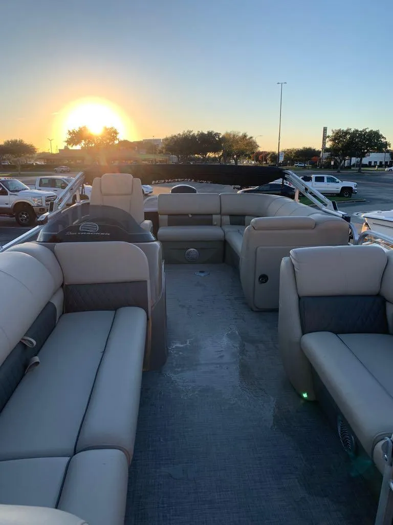 Slide: The Image of 2023 Sun Tracker Party Barge 20 DLX pontoon boat with outboard motor, parked on trailer. - 2