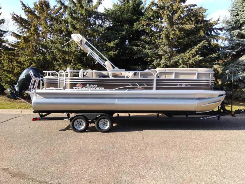 The Image of 2023 Sun Tracker SportFish 22 DLX pontoon boat on trailer, parked outdoors. - 0