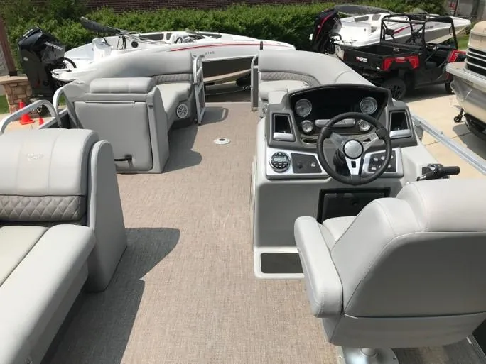 Slide: The Image of 2023 Ranger Reata 220C pontoon boat interior with gray seating and modern dashboard. - 11