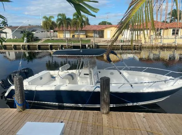 Slide: The Image of 2000 Stamas 290 Tarpon boat docked by a canal with palm trees in the background. - 1